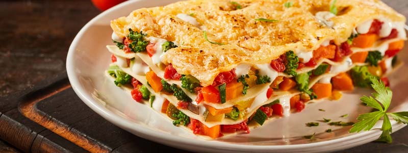 Tasty portion of Italian vegetable lasagna with melted mozzarella, colorful fresh veggies and pasta serced on a plate as a healthy appetizer
